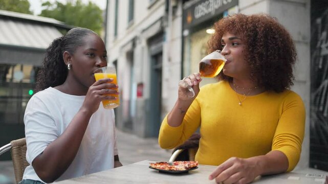 Multiethnic two woman friends sharing an aperitif and refreshments and having a good time. Gen z.