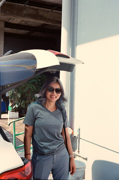 Casual portraiture of a curly dyed hair lady posing with car trunk