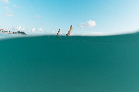 Two people doing handstands in the water