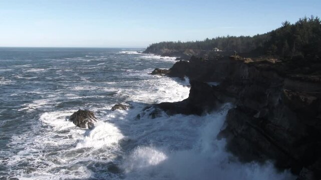 Wide establishing shot at the Oregon Coast during king tides as waves crash on rugged coastline.