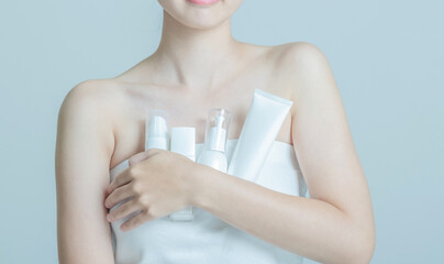 Close-Up of a Woman Holding Skincare Bottles Against Her Chest