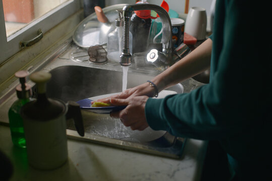 a woman washing a plate in really hot water