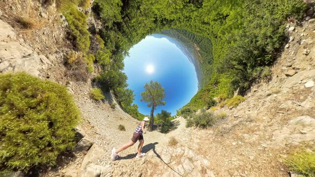 A Woman walking along a cliffside path, captured with a Rabbit Hole Planet effect. The circular composition distorts the Landscape, with the Sun at the center for a surreal visual.