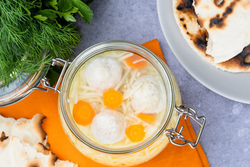 Matzoh ball soup, noodle, vibrant carrots on a gray background. Jewish traditional cuisine Passover food. Healthy festive food. top view