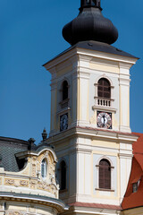 A baroque-style church tower in Sibiu, Romania, featuring an onion-shaped dome, a clock face, and arched windows.                  
