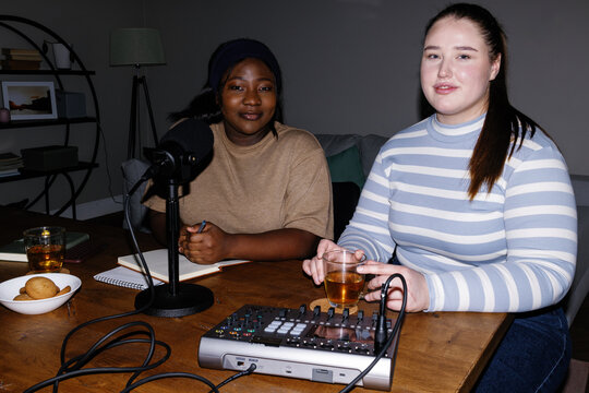 Flash photo of female content makers creating podcast at home office