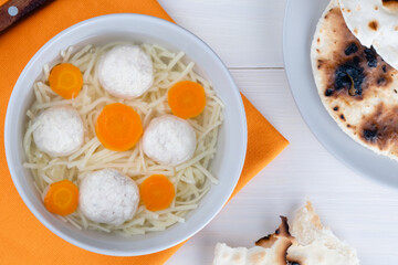 Matzoh ball soup, noodle, vibrant carrots on a gray background. Jewish traditional cuisine Passover food. Healthy festive food. top view