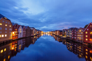 Trondheim in the blue hour, the houses on piers near the river flowing through the town in the evening with blue skies and reflections