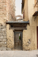 This quaint stone house in Nafplio features a weathered wooden door, inviting exploration while blending seamlessly with its historical surroundings and vibrant atmosphere.