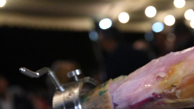 Close up of chef hands cutting a delicious slice of cured ham - Chef cutting Spanish serrano ham, Serving serrano ham preparing food in a kitchen 