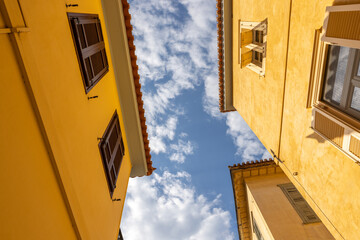 Beneath the vibrant yellow facades of Nafplio's traditional houses, a stunning sky emerges, merging...