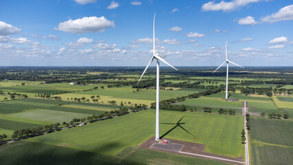 Landscape photo of two wind turbines in meadow farming field. Green renewable energy, global warming, climate change, sustainability, farm land concept. 