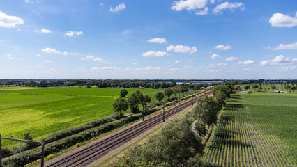 Landscape with railroad train line and meadow farm fields drone view.