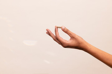 Hand Holding Pill Against Minimalist Background