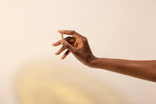 Hand Holding a Pill Against a Soft Background