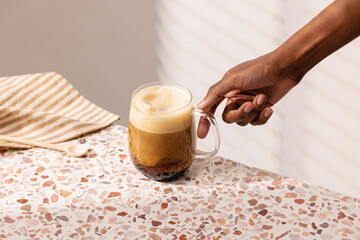 Hand Reaching for Coffee Mug on Terrazzo Table in Bright Room