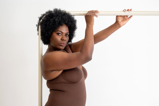 Curvy Black Woman In Shapewear Bodysuit Holding Onto Bar
