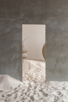 Minimalist interior with doorway leading to sandy floor and large vase