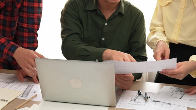 Smart architect and safety engineer discussion about building plan on table with architectural document, measurement tools and wooden block scatter around at modern office. Closeup. Delineation.