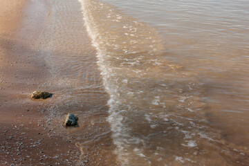 Swirling ripples surround the rocks as the waves from Lake Michigan recede to wash onshore again, in late afternoon during May at Harrington Beach State Park, Belgium, Wisconsin