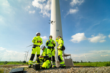 Electric engineer wearing Personal protective equipment working at wind turbines farm .  Wind turbine technicians doing wind turbine blade inspection with drone.