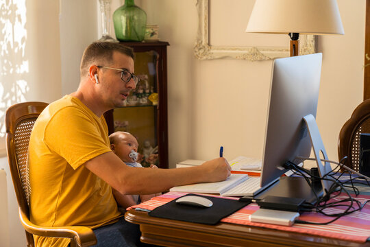 Dad working on the computer while holding the baby