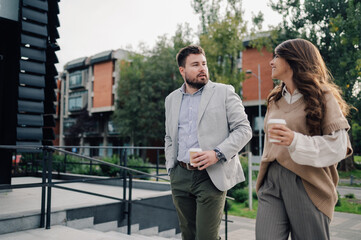 Business people having informal meeting while walking outdoors and holding takeaway coffee