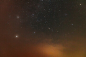 Obraz premium A peaceful night sky filled with faint stars and a soft red aurora glow near the horizon. The cosmic scene blends dark space with atmospheric colors, creating a dreamy, tranquil view.