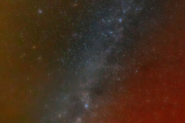 A mesmerizing night sky filled with countless stars and a subtle nebula, displaying a gradient of colors from red to green. The scene captures the vastness and beauty of the universe.