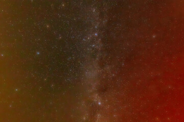 A mesmerizing night sky filled with countless stars and a subtle nebula, displaying a gradient of colors from red to green. The scene captures the vastness and beauty of the universe.