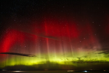 A stunning display of red and green auroras lighting up the night sky, with stars sparkling in the background. The vibrant celestial event creates a mesmerizing, ethereal atmosphere.