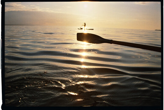 Oar Dipping Into Water at Sunset