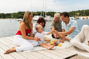 Family with Children and Grandparents Enjoying Picnic on Jetty