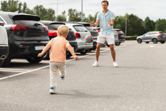 Dad Playing Football with Young Son in Car Parking Lot