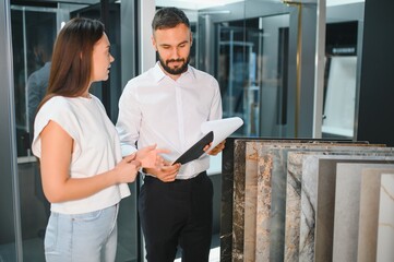 Salesman and a female customer choosing a right ceramic tile for her home, at the home design store