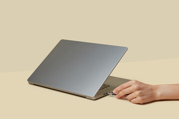 Hand of unknown human inserting external memory drive to laptop