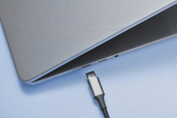 Grey netbook laying on blue surface next to micro usb wire
