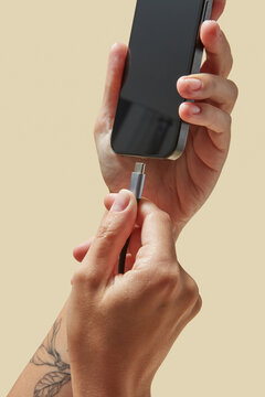 Cable with metal plug under mobile phone in hands of gadget user