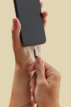Unseen woman keeping mobile telephone with type c charging cable