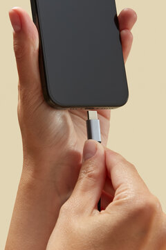 Person holding mobile telephone and attaching usb cable