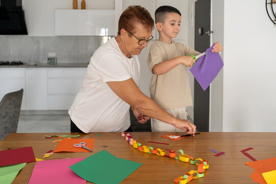 Kid And Senior Woman Make Colorful Paper Chain for Sukkot or Christmas