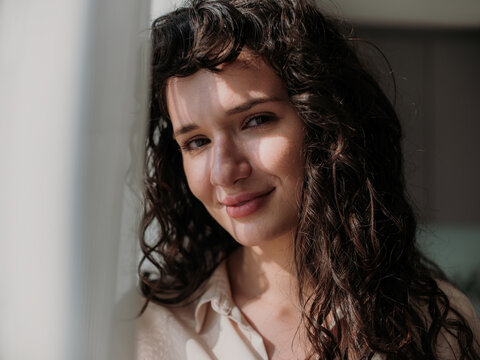Beautiful Curly Haired Young Woman Smiling at Home in Bedroom