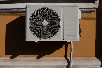 Outdoor air conditioner unit hanging on wall of house, external part of air conditioner to cool...
