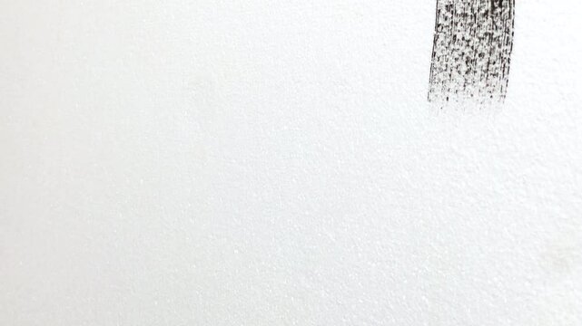 brush painting a white wall with black paint