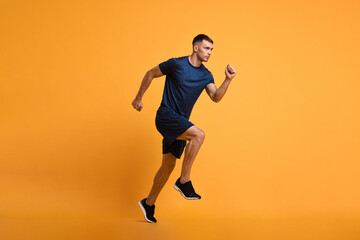 Fototapeta na wymiar Man in sportswear running on orange background
