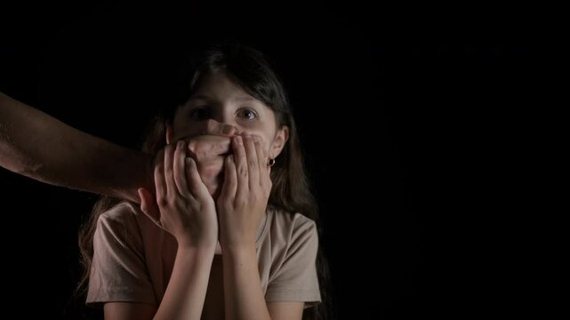 The man covers the child's mouth with his hand. A view of man put her palm on child mouth to stop speaking. A concept of interdiction or taboo during childhood.