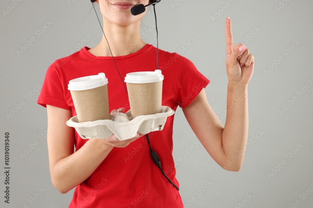 Wall mural Fast-food worker with paper cups on gray background, closeup