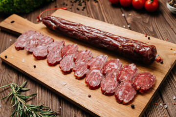 Smoked salami sticks on a wooden board with herbs, perfect for charcuterie boards and gourmet snacks