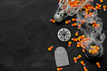 Tasty Halloween candy corns, skeleton and cookies on dark background