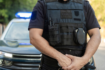 Police officer guarding and protecting standing near patrol car with lights flashing